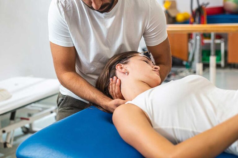 Parent watches as a child receives a gentle musculoskeletal assessment in a bright clinical room.