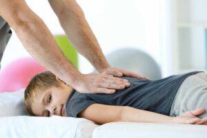 Patient speaking with a chiropractor during a first-visit health assessment in a bright clinical room.